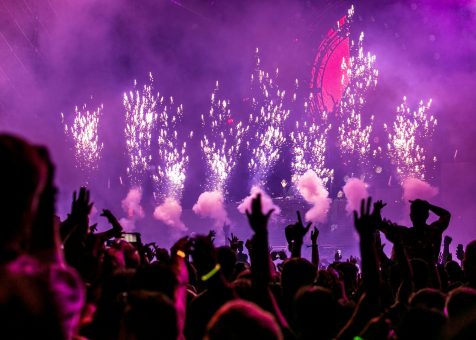 Vibrant EDM concert scene with fireworks, smoke, and enthusiastic crowd enjoying the music.