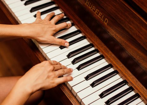 Musician's hands playing wooden piano keys in a high contrast image, capturing musical expression.