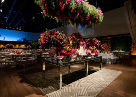 A beautifully decorated wedding venue with vibrant floral arrangements and elegant table settings under romantic lighting.