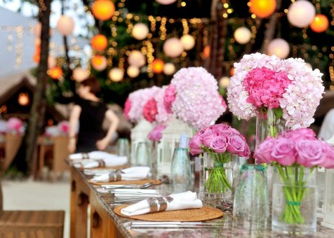 Elegant outdoor wedding setup featuring pink floral arrangements and soft lighting.